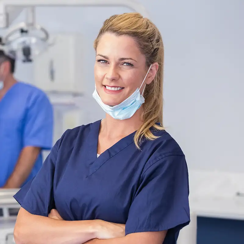 Dental staff with face mask smiling and standing with arms crossed