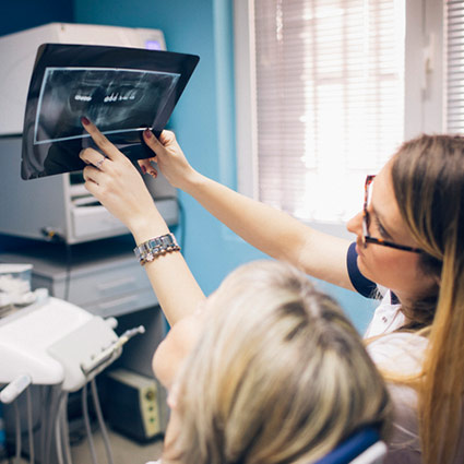 Dental assistant reviews x-rays with a patient prior to her oral surgery procedure