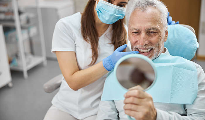 a man and doctor evaluating his new dental implants in a mirror