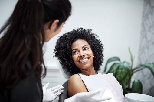 Beautiful Black woman speaking with dentist after getting a sinus lift from Mountain State Oral and Facial Surgery in Charleston, WV