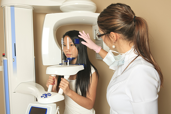 Dental assistant helping patient to get ready for a 3D cone beam scan