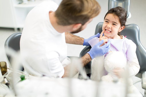 Little girl smiling in dental chair with dentist