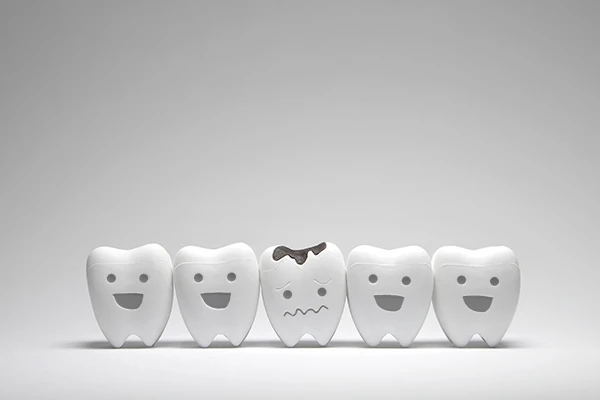 Row of five toy teeth, all smiling except for the middle tooth which frowns because of tooth decay in Charleston, WV