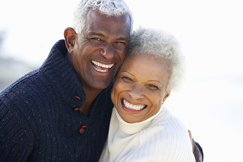  Older Black couple smiling after booking a dental implant at Mountain State Oral and Facial Surgery 