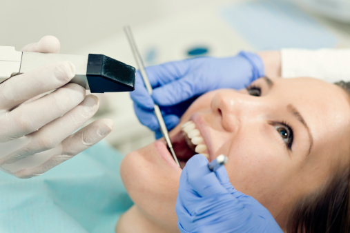 A woman's teeth being scanned by an intraoral camera