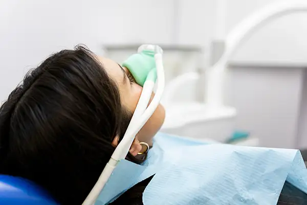Patient receiving nitrous oxide sedation through a mask during a dental procedure.